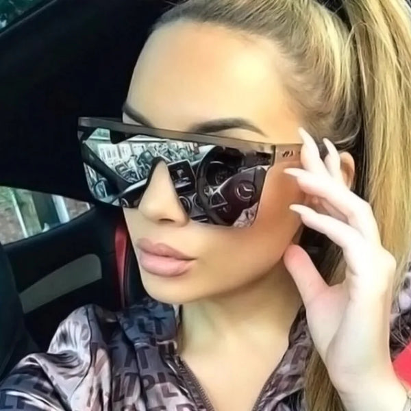 Model wearing oversized black wraparound sunglasses inside a car