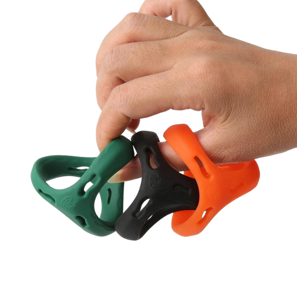 Hand holding three silicone penis rings in green, black, and orange