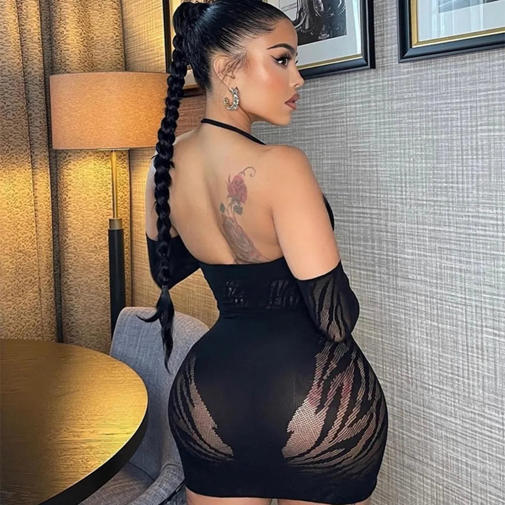 Back view of a model in a black fishnet-panel dress with long braid and back tattoo