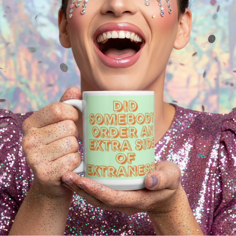 Person in a glittery sequined top holds a mint-green mug reading “DID SOMEBODY ORDER AN EXTRA SIDE OF EXTRANESS?”