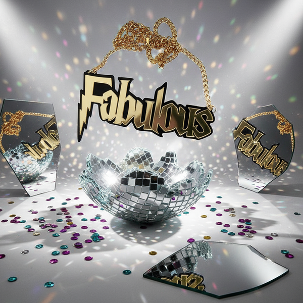 Close-up of a gold acrylic “Fabulous” statement necklace on a disco-themed mirrored backdrop