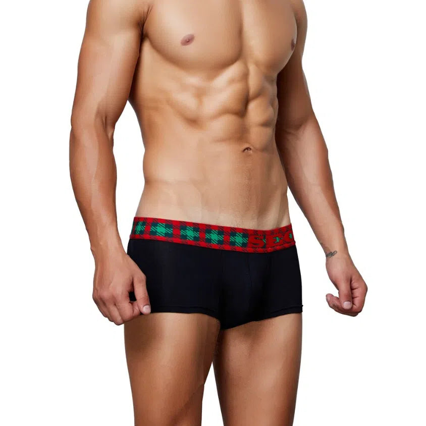 Front view of a model wearing black boxer briefs with a red and green tartan waistband