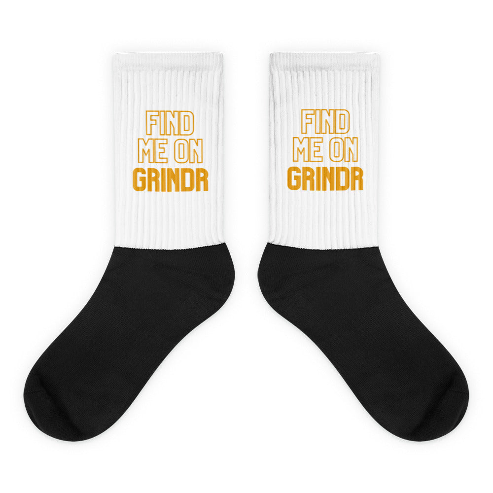 Pair of black-and-white crew socks reading “FIND ME ON GRINDR” in orange