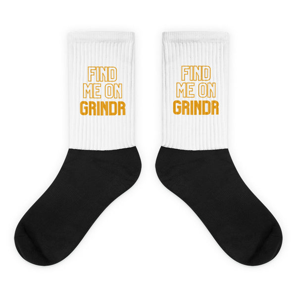 Pair of black-and-white crew socks reading “FIND ME ON GRINDR” in orange