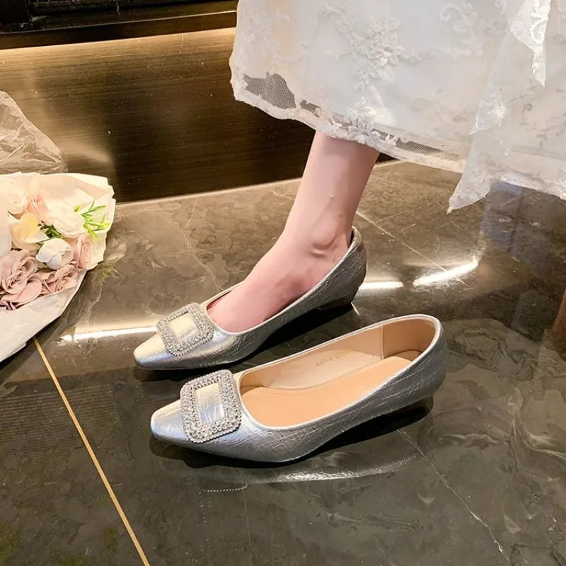 Silver rhinestone-buckle pumps, one worn beneath a white lace dress and one on a marble floor