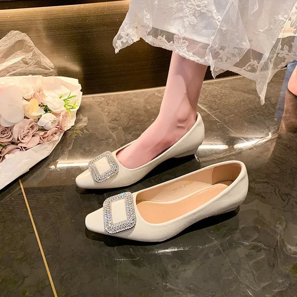 White pointed-toe pumps with rhinestone buckles, one worn beneath a lace hem
