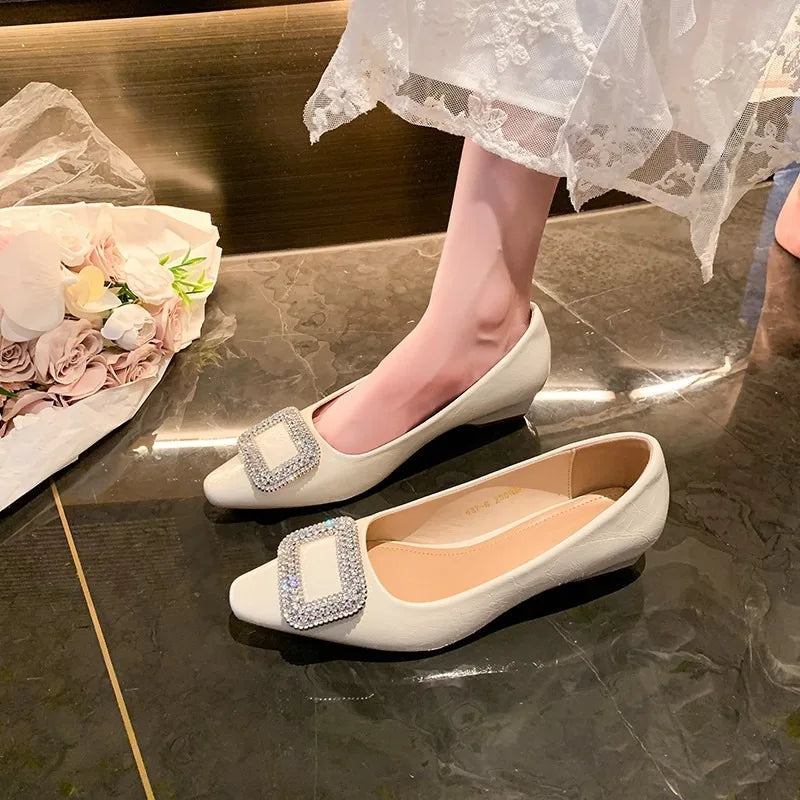 White pointed-toe pumps with rhinestone buckles, one worn beneath a lace hem