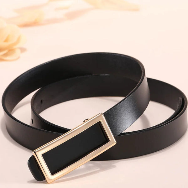 Coiled black leather belt with a large rectangular gold-tone buckle, shown on a pale surface