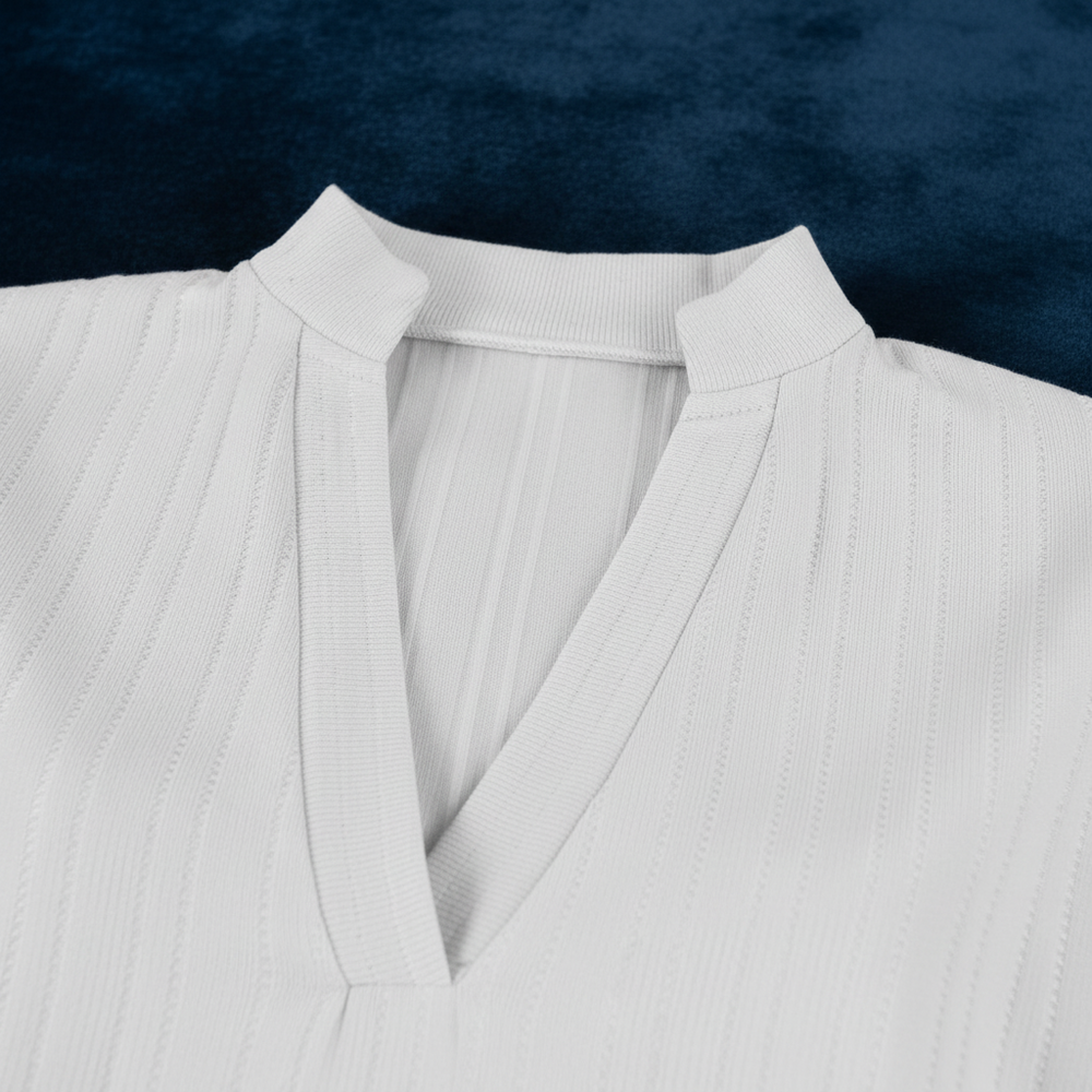 Close-up of a white textured blouse with a V-neck and pointed collar