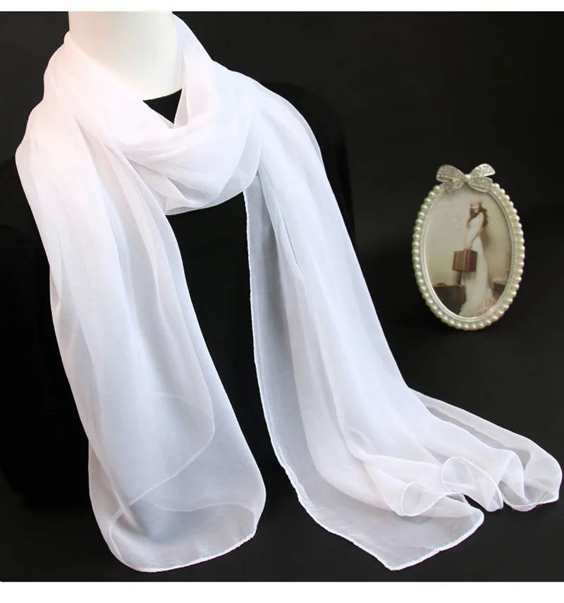 White sheer scarf draped around a headless mannequin, with a small oval mirror beside it