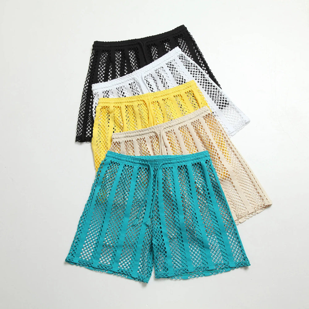 Flat lay of five colorful open-mesh shorts in black, white, yellow, beige, and turquoise