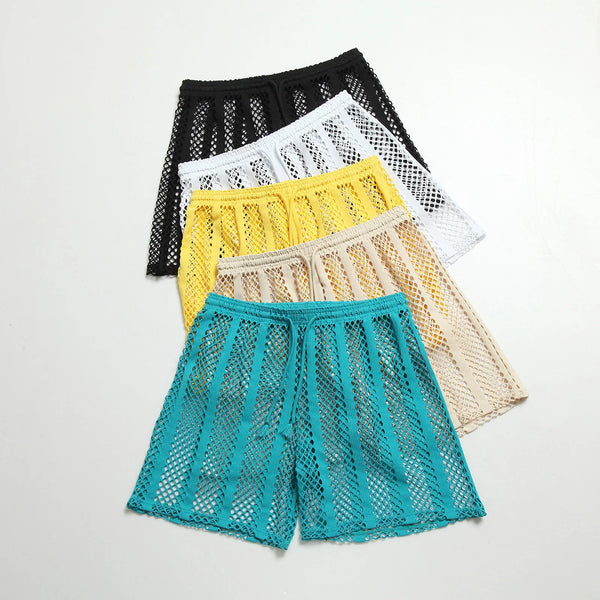 Flat lay of five colorful open-mesh shorts in black, white, yellow, beige, and turquoise