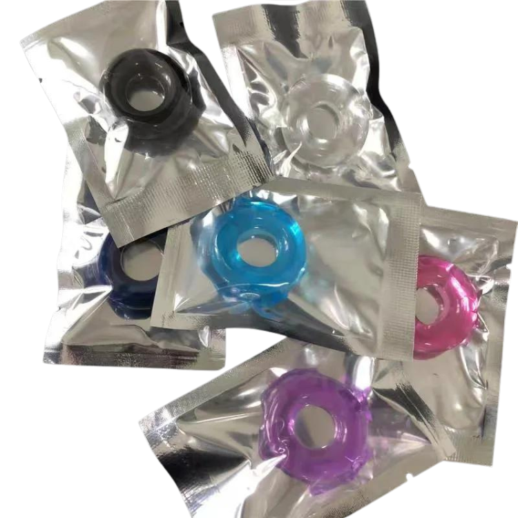 Six colorful silicone penis rings individually sealed in silver packets, overlapping on white