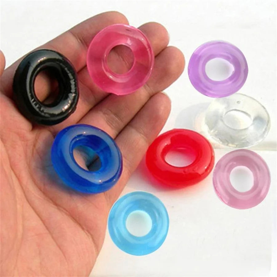 Seven translucent silicone cock rings in assorted colors, with several resting in an open hand