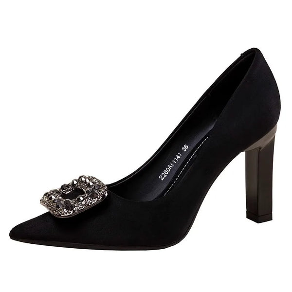 Black pointed-toe pump with a tall block heel and jeweled buckle, shown from the side
