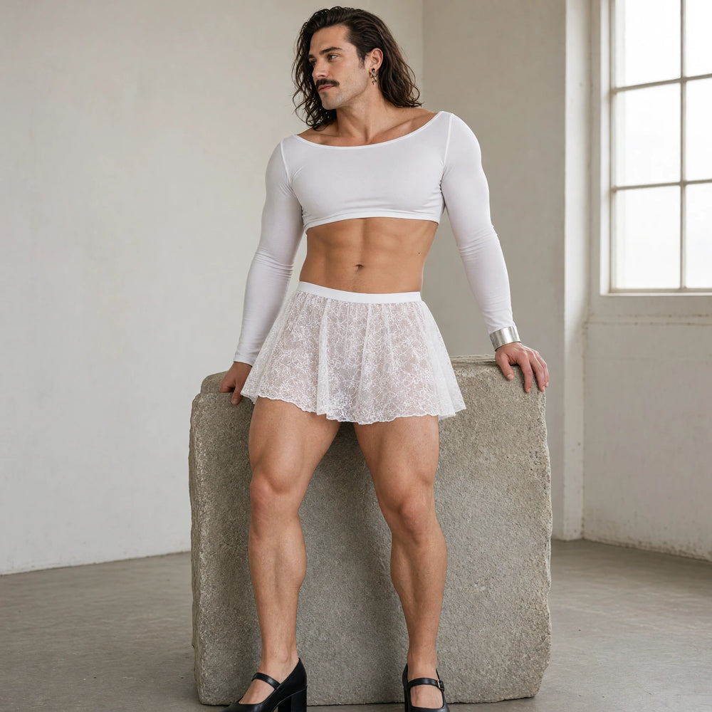 Model wearing a white floral lace mini skirt over opaque shorts with a white crop top in a sculpture studio
