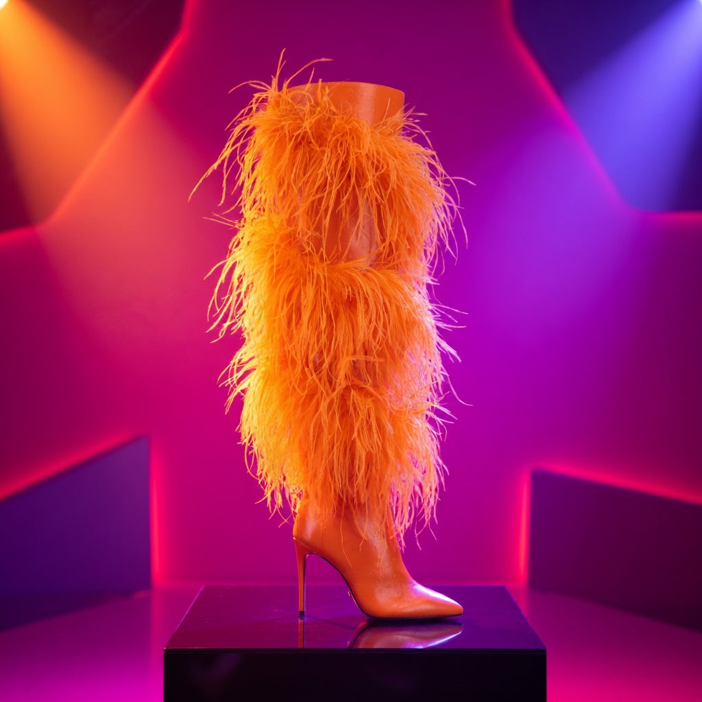 Side view of an orange pointed-toe stiletto boot with shaggy faux-fur shaft