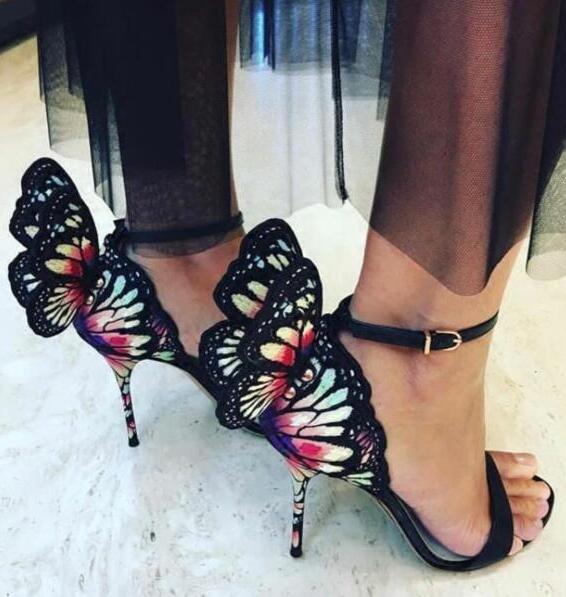 Close-up of black butterfly-wing stiletto heels with colorful wings and ankle straps