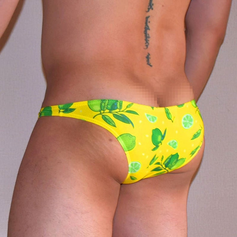 Rear three-quarter view of a model wearing bright yellow citrus-print swim briefs