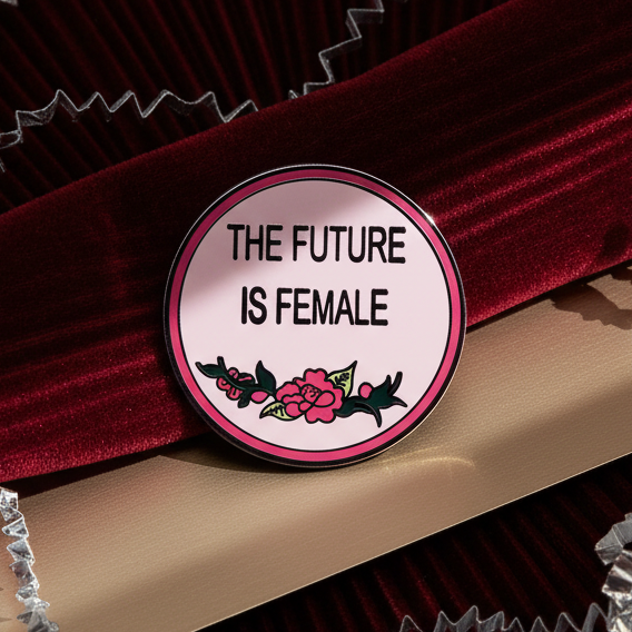Close-up of a round enamel pin reading “THE FUTURE IS FEMALE” with floral artwork