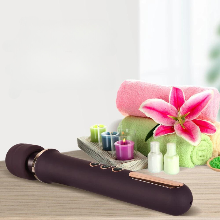 Dark purple AV wand vibrator on a wooden surface with towels, candles, and a pink lily