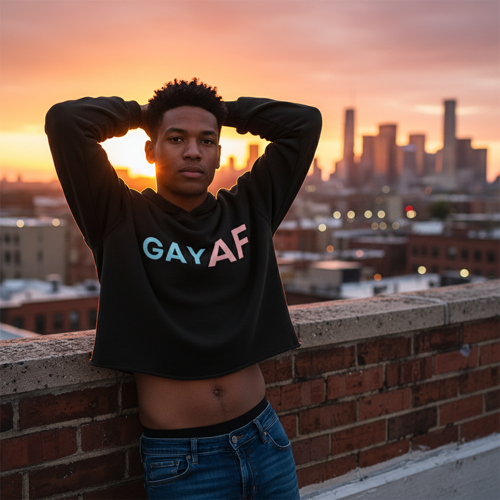 Gay AF Crop Hoodie in black, bold rainbow "GAY AF" text; person poses rooftop at sunset, orange sky, city skyline