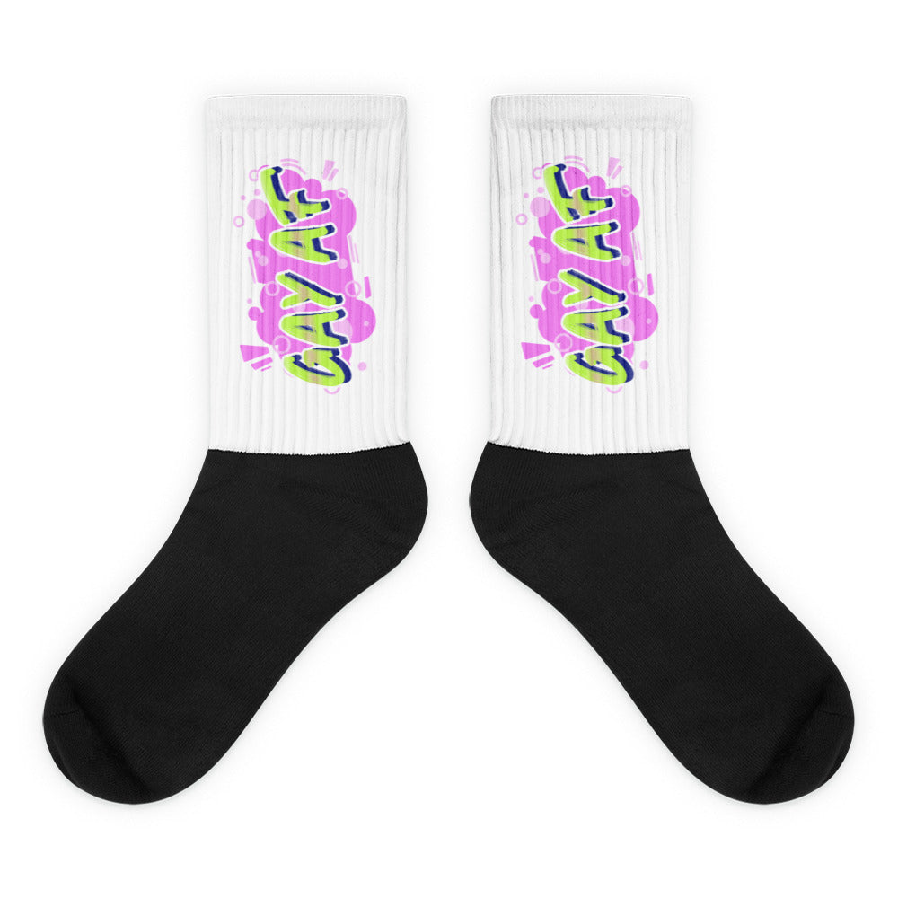 Pair of crew socks with black feet and white ribbed cuffs reading “GAY AF” in neon colors