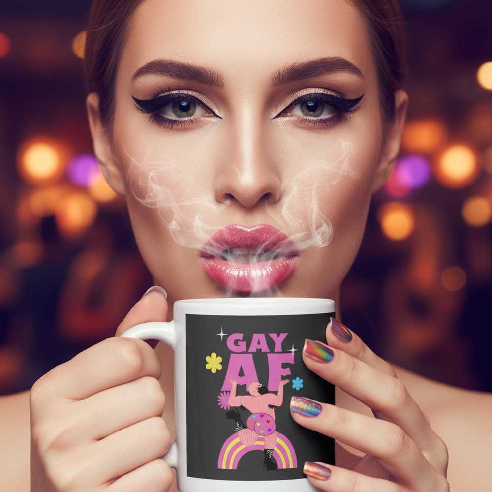 Person holds a steaming white mug labeled “GAY AF” with a colorful figure and rainbows