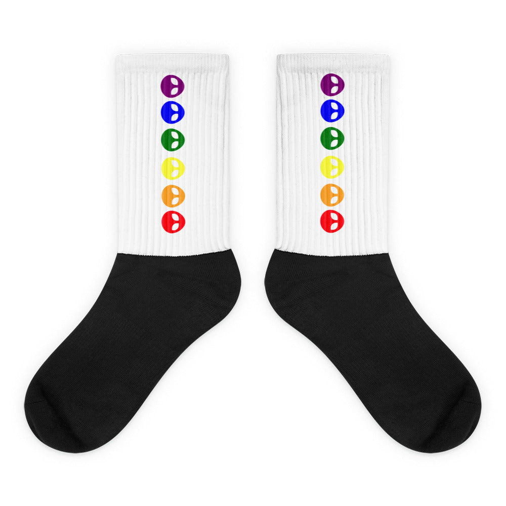 Pair of black-and-white crew socks with vertical rainbow alien-face icons