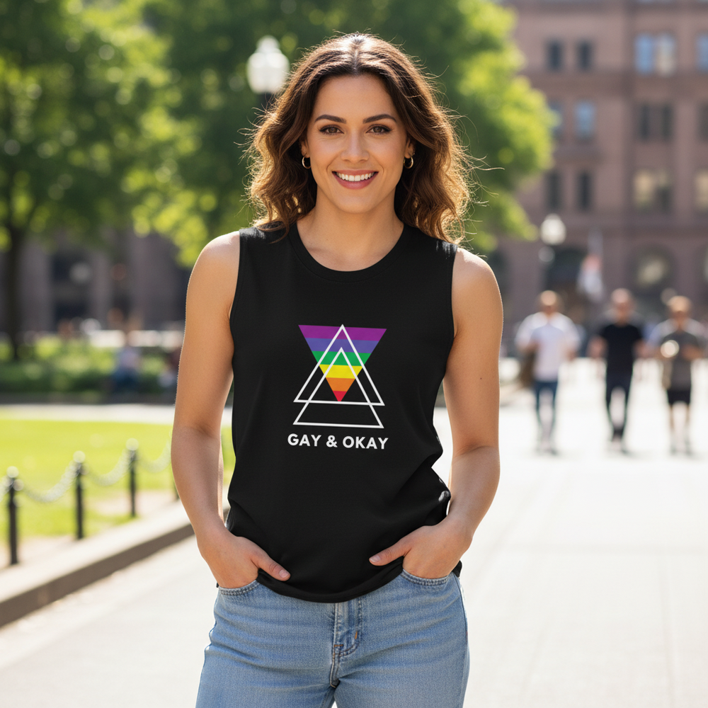Gay & OK Muscle Top with a geometric rainbow design, worn by a smiling person outside