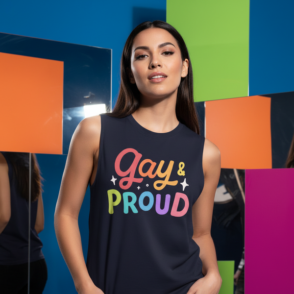 Gay & Proud Muscle Top with rainbow lettering, worn by a person with long dark hair, posed in front of bold blue, orange