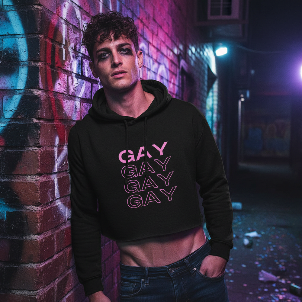 Model wearing a black cropped hoodie with four pink “GAY” prints in a graffiti-lit alley