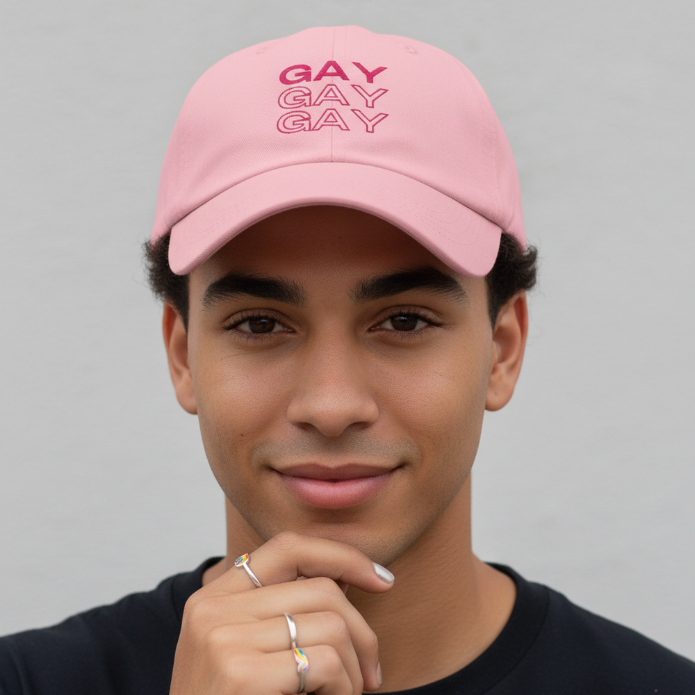 Front-facing model wearing a pink cap with “GAY” printed three times