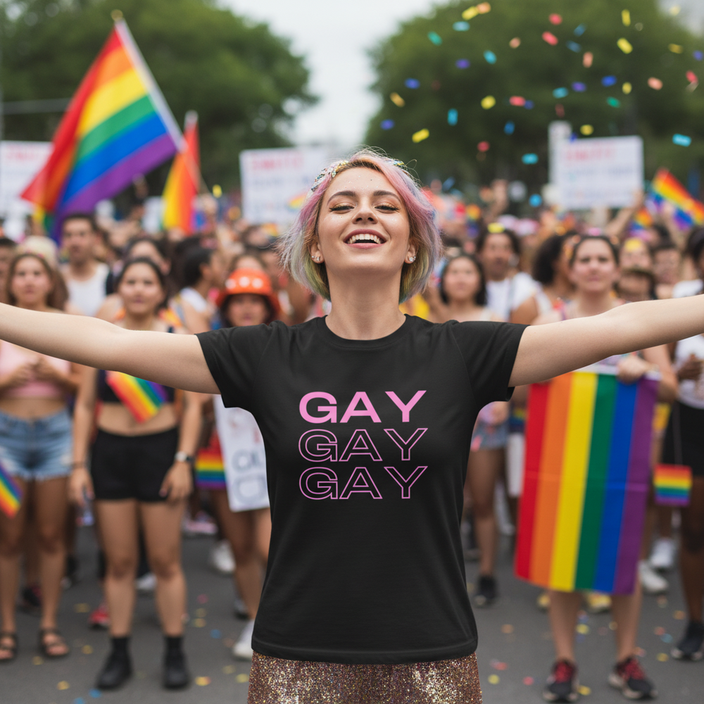 Pink-haired person in a black “GAY GAY GAY” shirt at a Pride parade