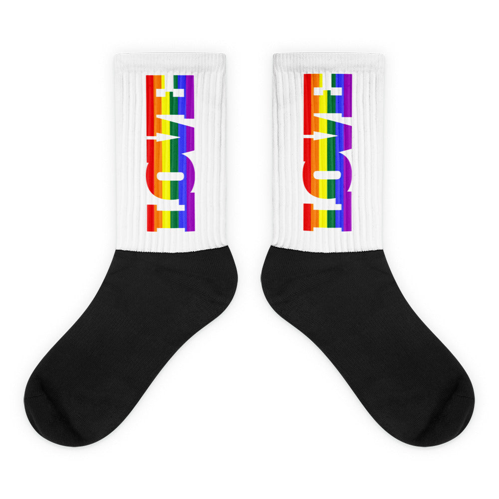 Pair of crew socks with black feet and rainbow-striped LOVE lettering on white cuffs