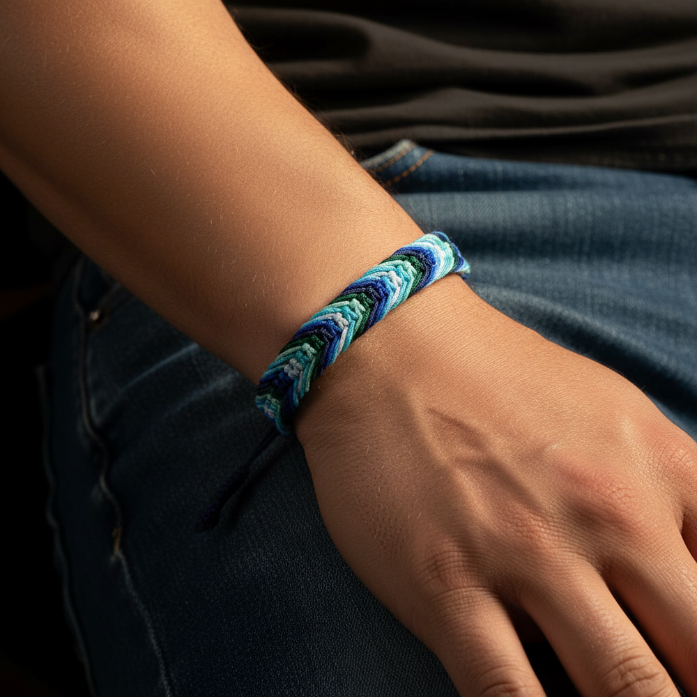 Close-up of a hand wearing a braided blue and teal friendship bracelet