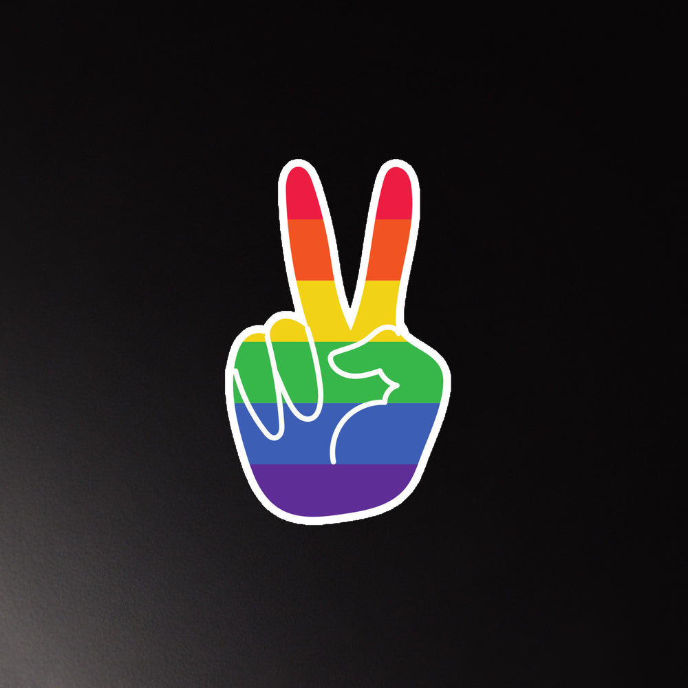 Rainbow-striped hand-shaped magnet showing a peace-sign gesture on a black background