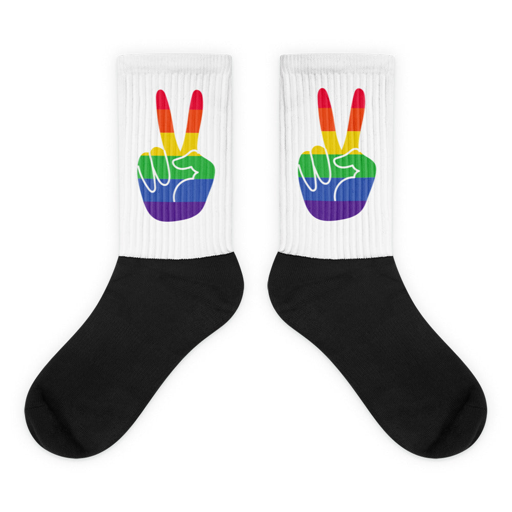 Pair of crew socks with black feet and white cuffs showing rainbow peace-hand graphics