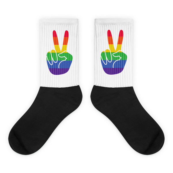 Pair of crew socks with black feet and white cuffs showing rainbow peace-hand graphics