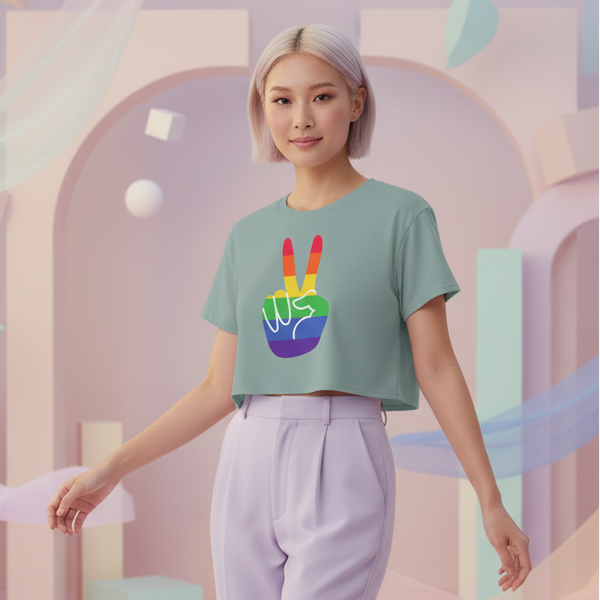 Model wearing a sage-green cropped T-shirt with a rainbow peace-sign graphic and lavender trousers