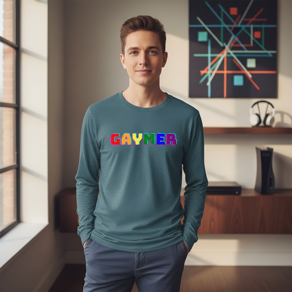 Gaymer Unisex Long Sleeve T-Shirt with "GAYMER" in rainbow letters, worn by a smiling person indoors in a sunlit