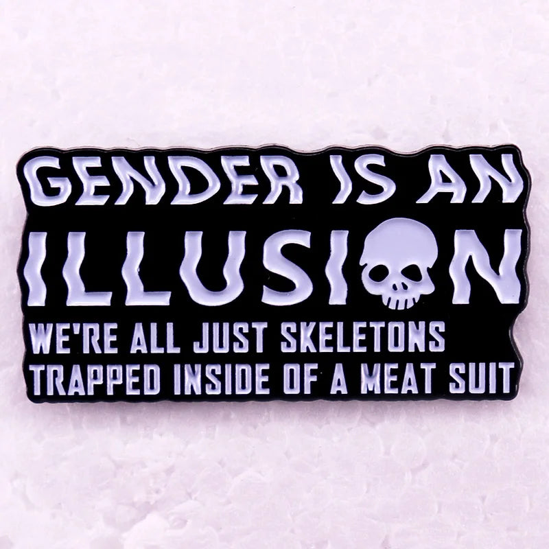 Black enamel pin reading “GENDER IS AN ILLUSION” with a skull and skeleton slogan