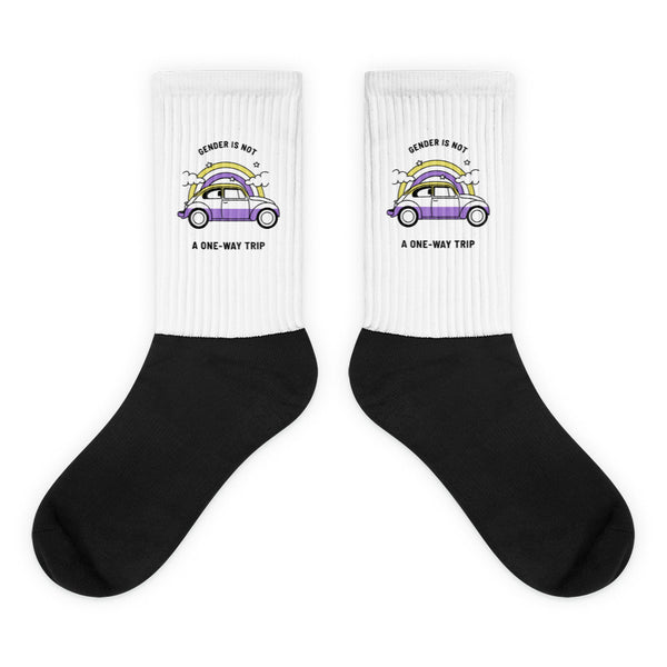 Pair of black-and-white crew socks with a purple car beneath a rainbow and text reading “GENDER IS NOT A ONE-WAY TRIP”