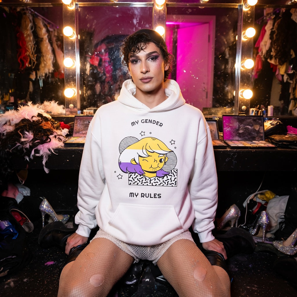 My Gender My Rules Unisex Hoodie with bold text and cartoon art, worn by someone chilling in a pink-lit queer dressing room.