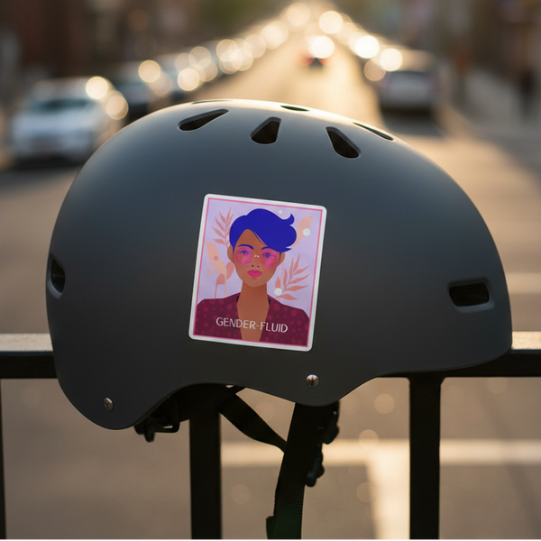 Matte black helmet on a fence, repping a bubble-free Gender-Fluid sticker: short blue hair, pink cheeks, leaves