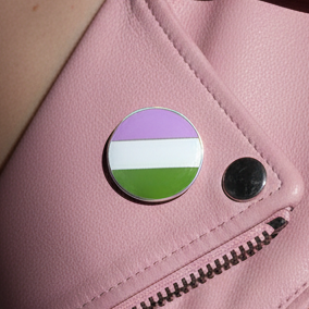 Close-up of a genderqueer pride enamel pin on a pink zippered bag