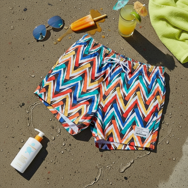 Flat lay of colorful zigzag swim shorts with a white drawstring on wet sand