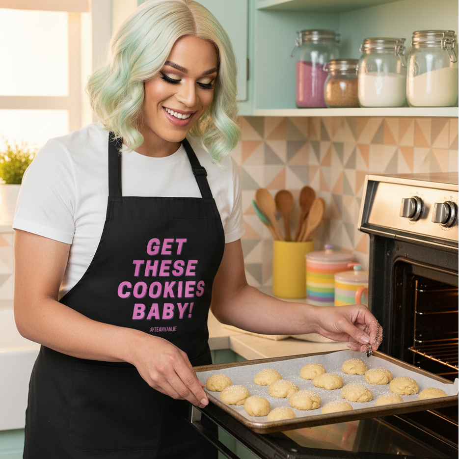 Person wearing a black “GET THESE COOKIES BABY!” apron slides cookie dough into an oven