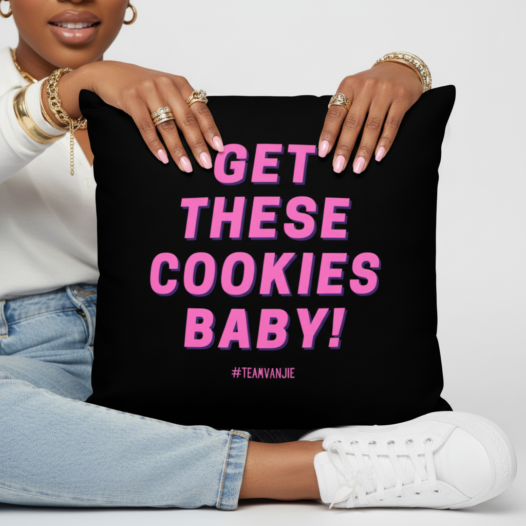 Hands with gold jewelry, light blue jeans, and white sneakers hold an LGBT pillow reading “GET THESE COOKIES BABY!” in pink