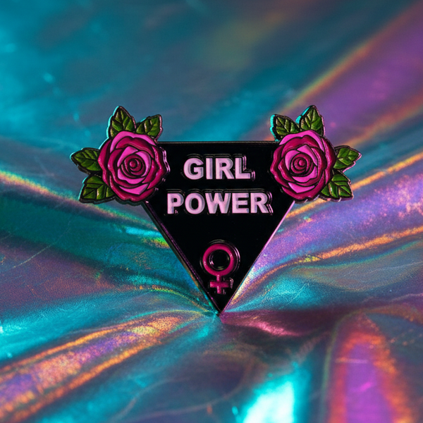 Close-up of a black triangular enamel pin reading “GIRL POWER,” with pink roses and a Venus symbol